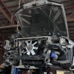 リフトアップされた日産スカイラインのエンジンルームを点検している様子。上越市ほしのじどうしゃの整備工場にて